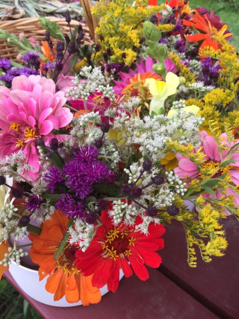 Photo shows a bouquet of bright, colorful flowers on a picnic table